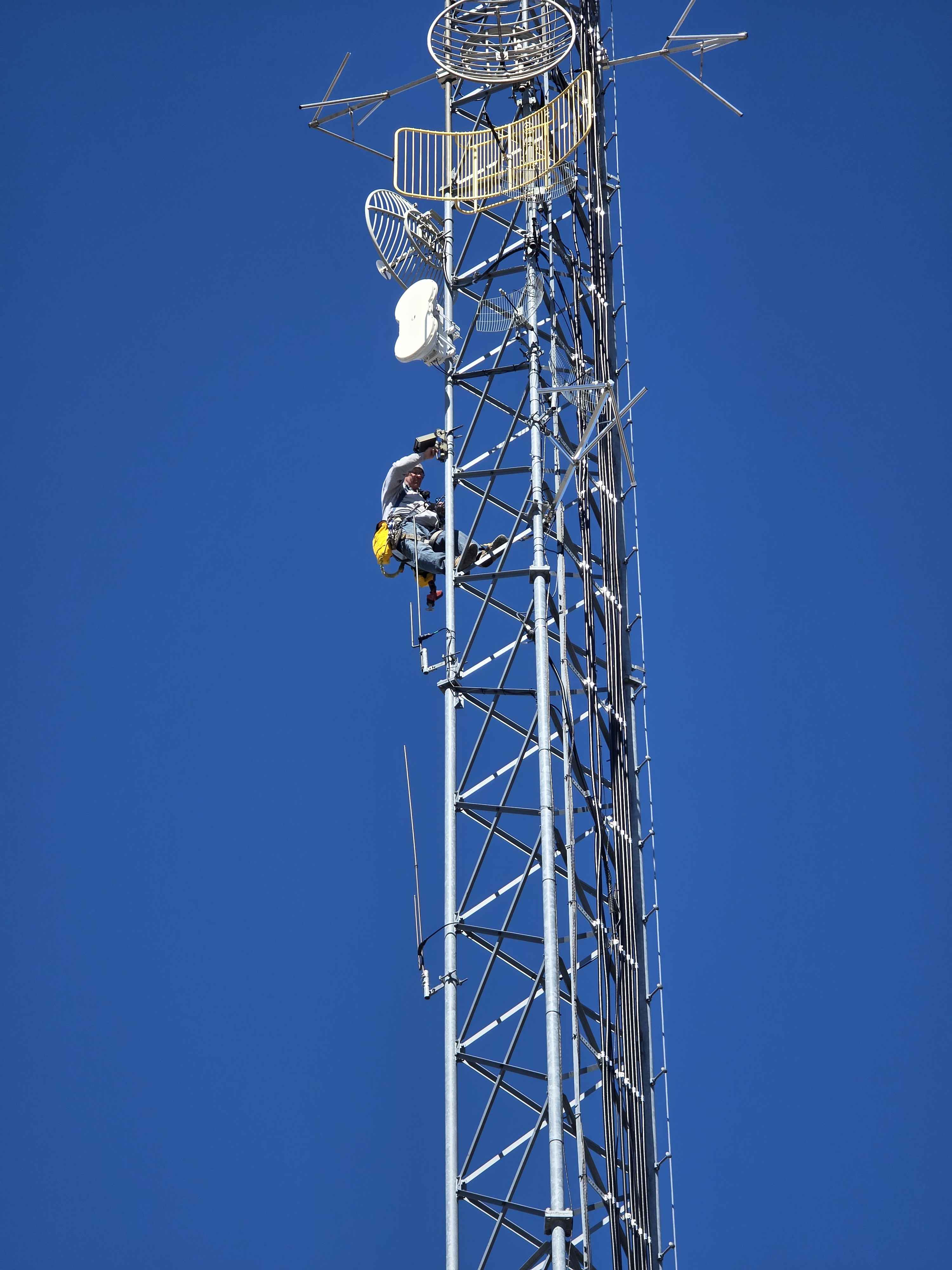 Climber working on the licensed tower carrying the Atlavox Beacon up for installation