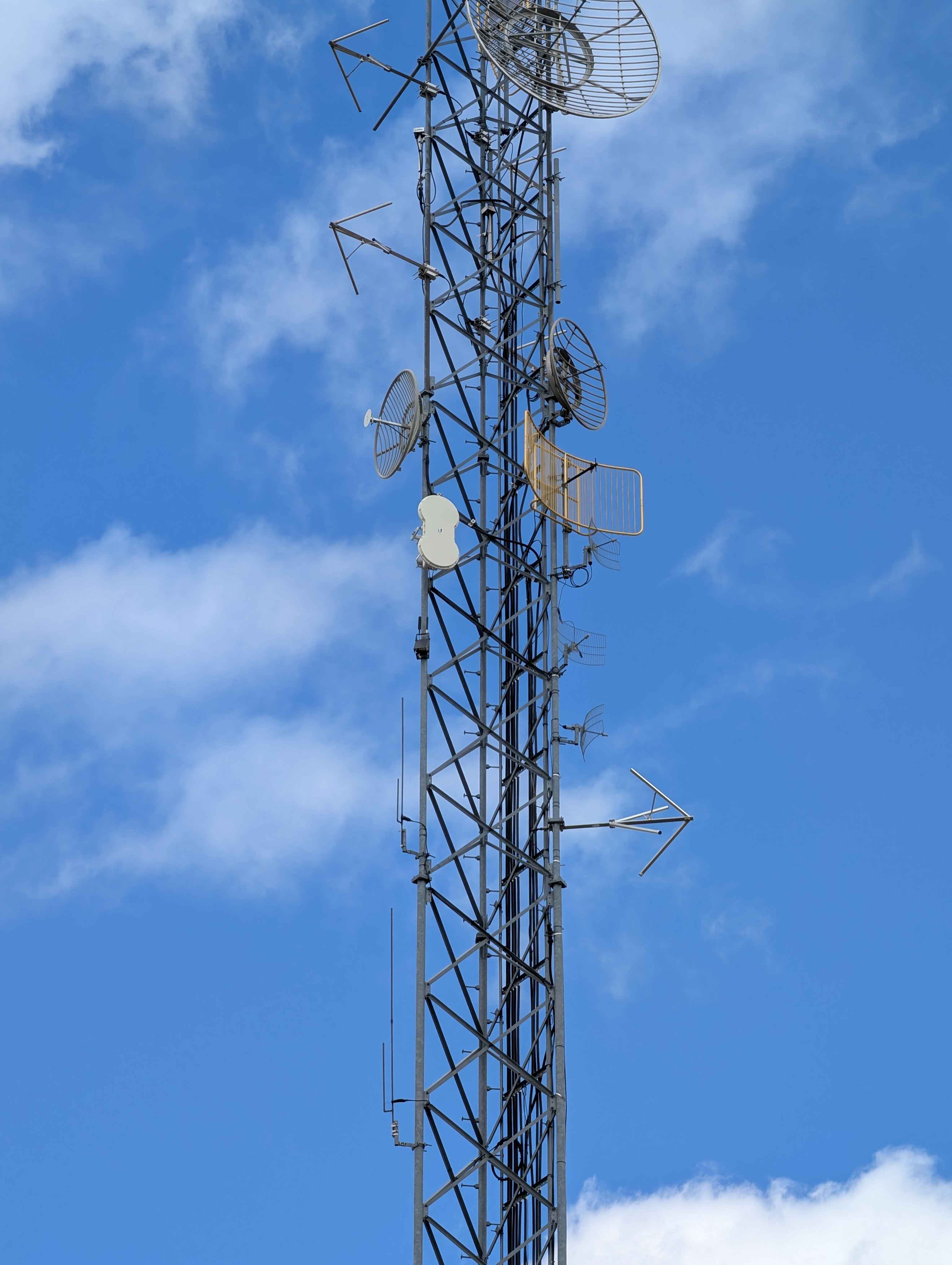 Atlavox Beacon mounted on the tower pole with both antennas vertical against blue sky