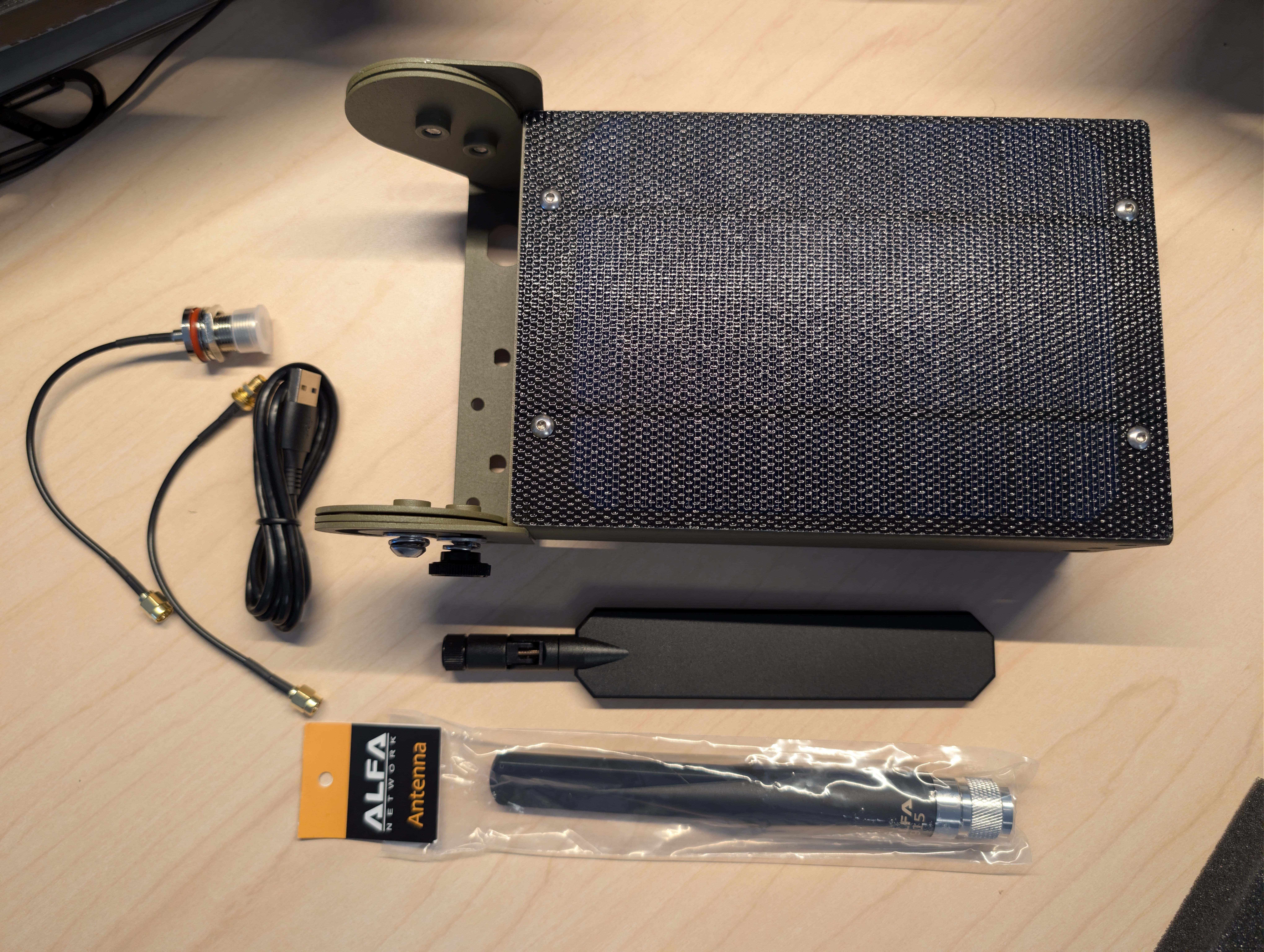 Atlavox Beacon enclosure laid out with Alfa 915 LoRa antenna, BLE antenna, USB-C cable, and solar pigtail