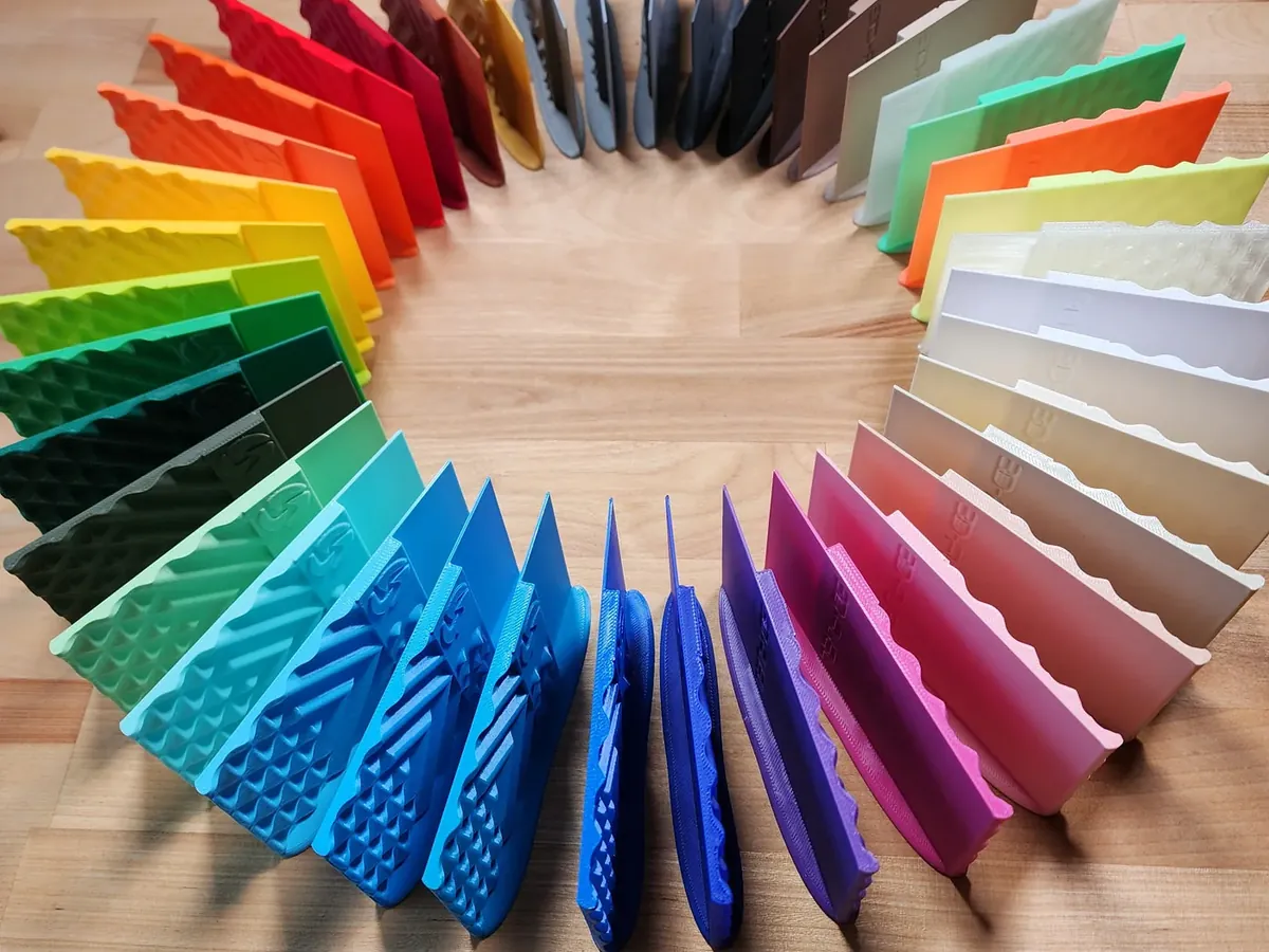 A ring of 3D printed sample swatches in dozens of 3D-Fuel filament colors on a wooden table