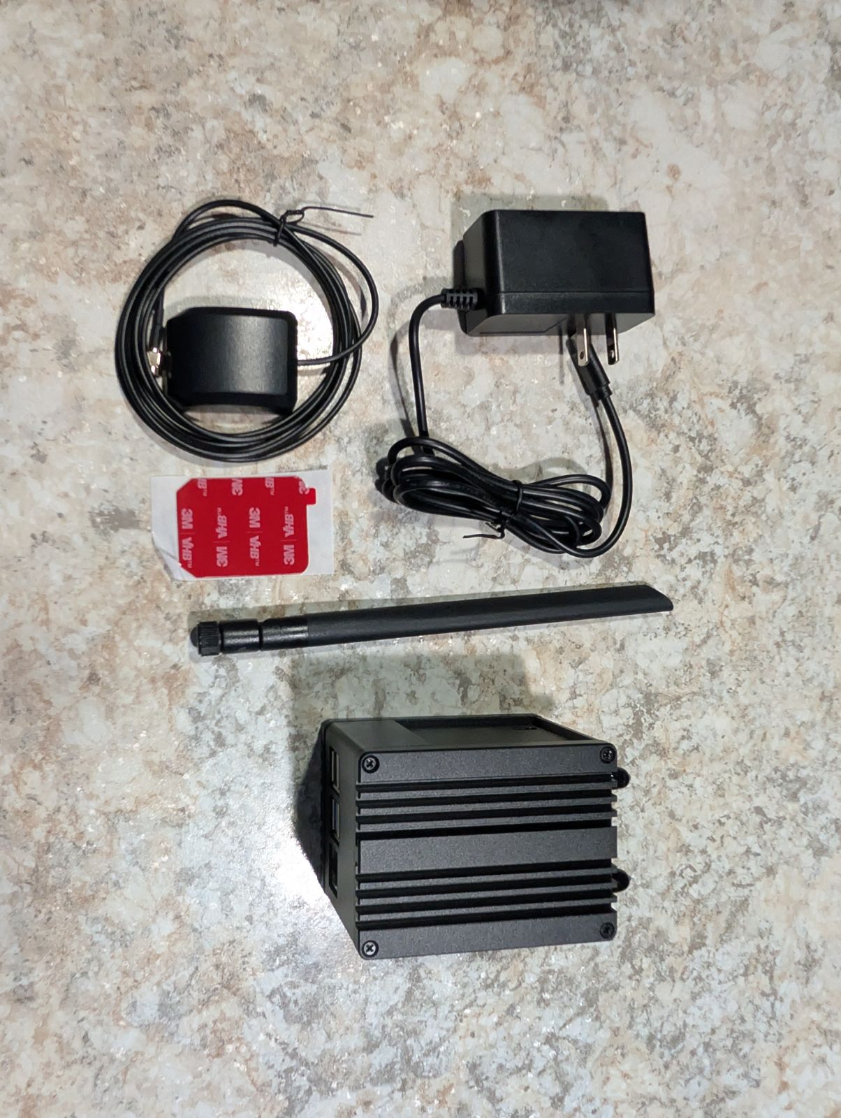 Everything in the WisMesh Station HP box laid out: GPS puck antenna on a cable with adhesive pad, wall power supply, LoRa whip antenna, and the unit