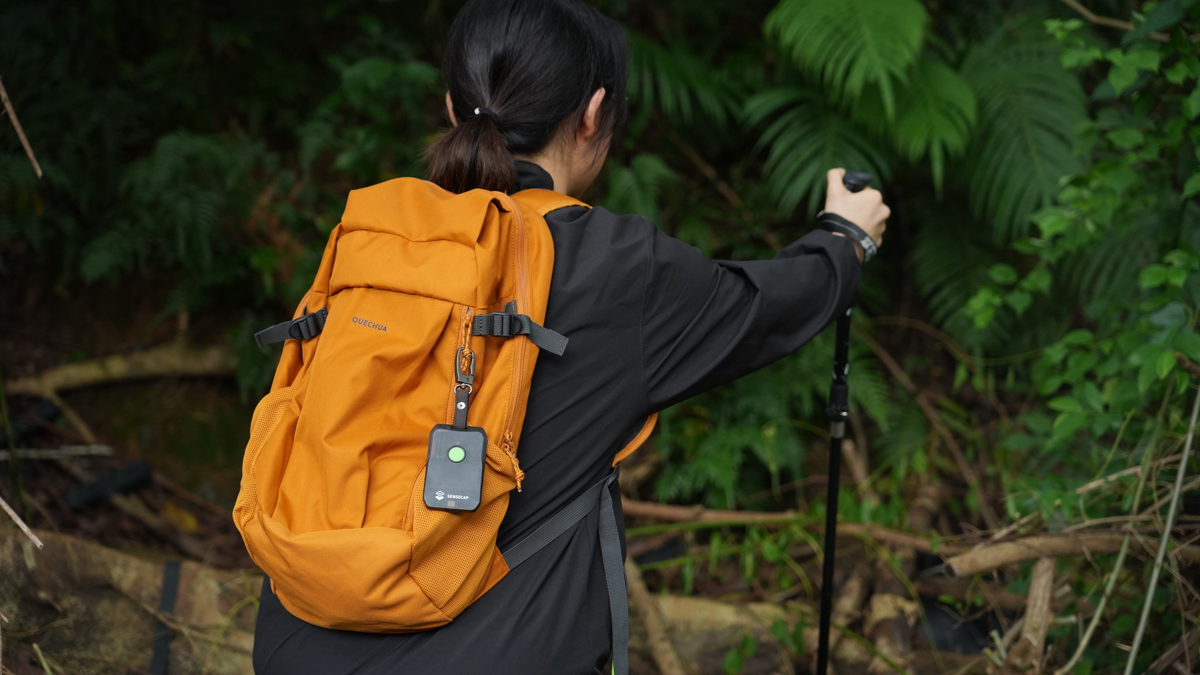 Hiker wearing a backpack with a SenseCAP tracker clipped to the shoulder strap